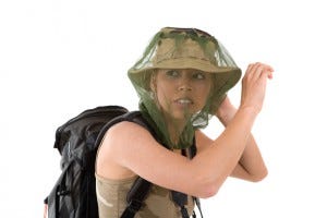 blond girl hiding her face behind a mosquito net that goes over her hat